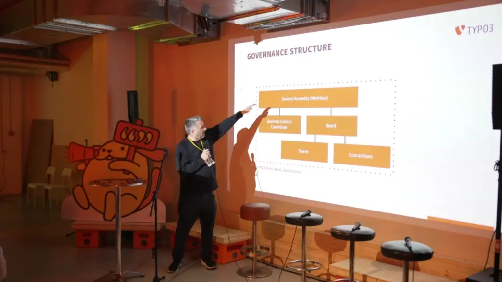 Olivier Dobberkau presenting the Typo3 Association governance.model, screen with slide, showing members above the boards